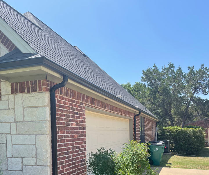 a home with brick outside walls, gutters, downspouts, and a garage