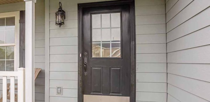 The home's square-framed front features a front entrance with glass panels and steps leading to the porch.